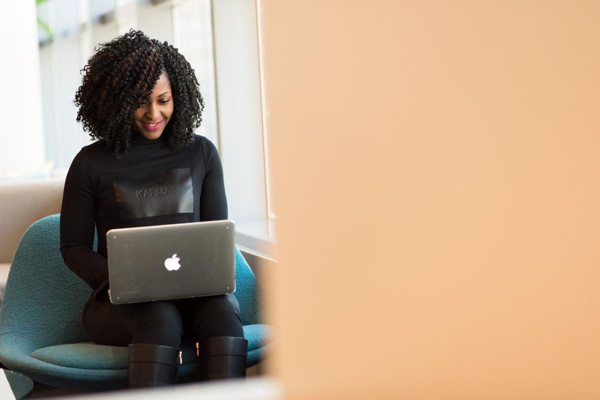 African American woman working on a laptop at a desk in a modern office setting