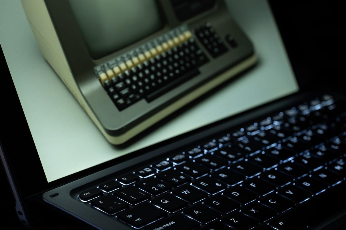 A vintage computer reflected on a modern laptop screen, showing old and new technology side by side