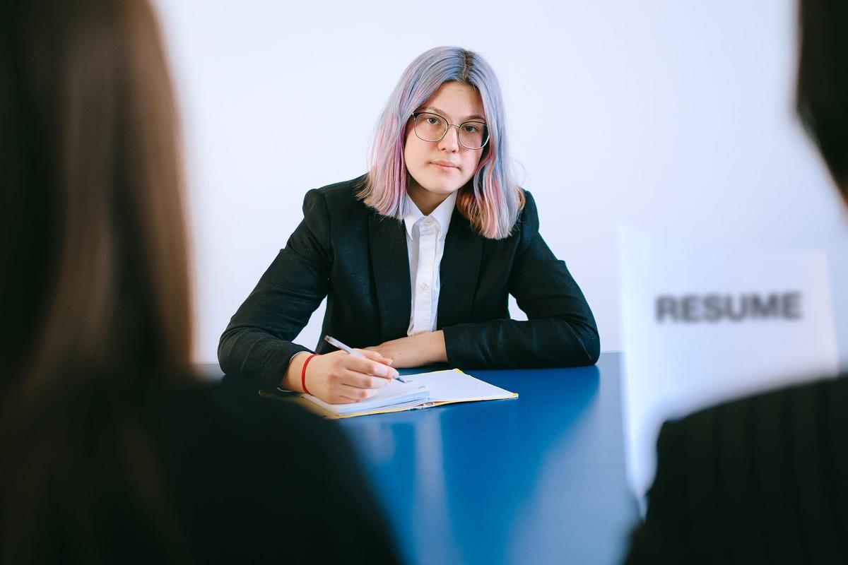 A young woman with dyed hair taking notes during a job interview