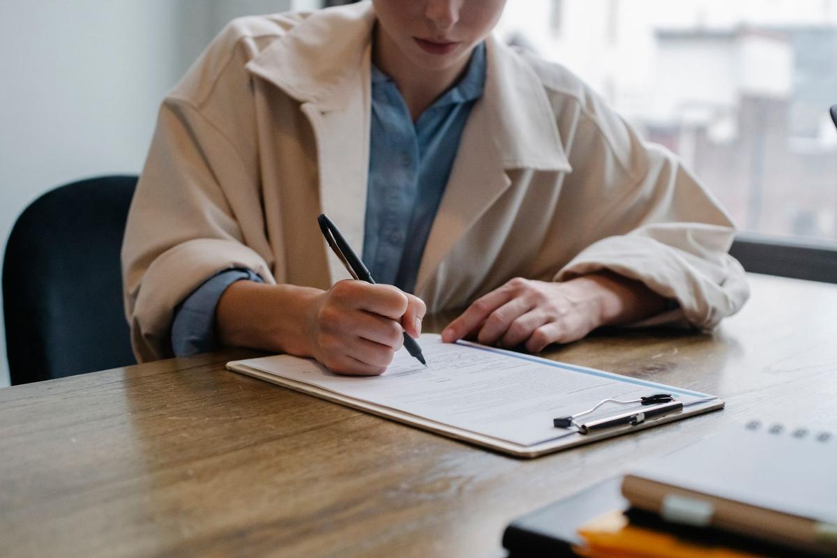 Young woman filling out a job application questionnaire at a table during an office interview