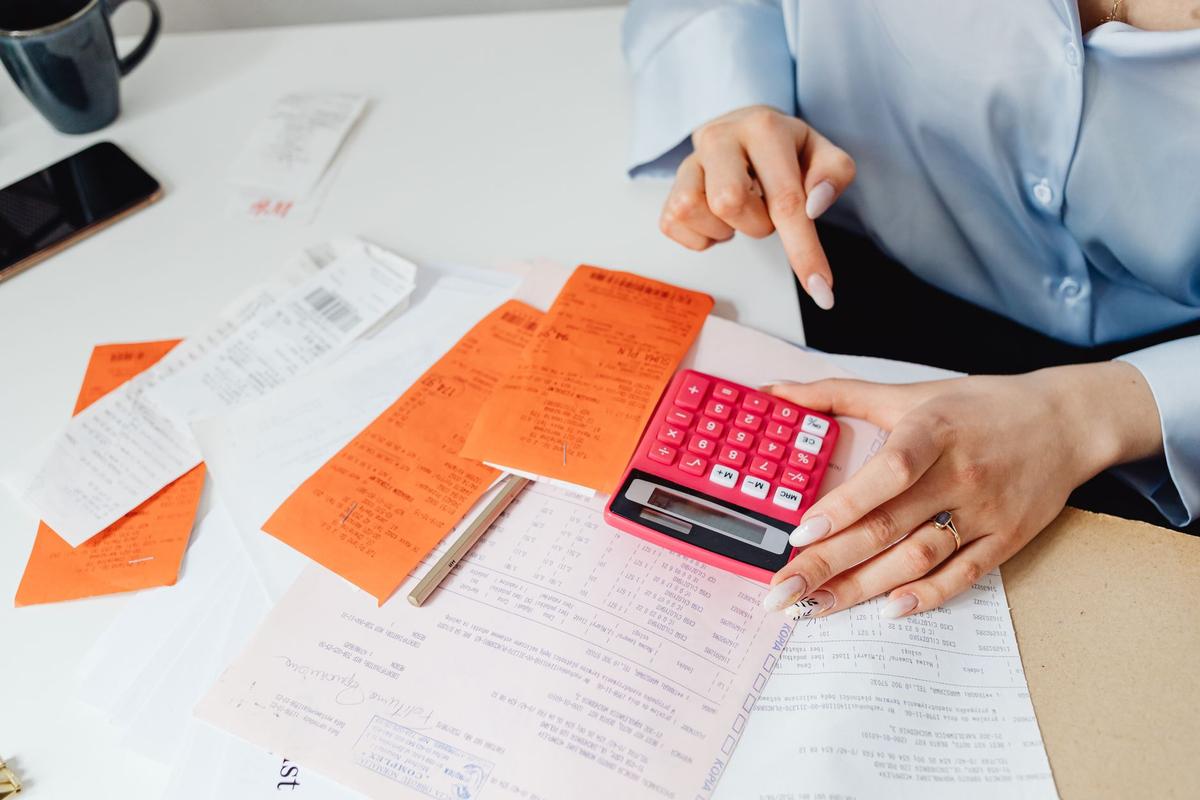 Businesswoman calculating expenses with receipts and a calculator at a desk